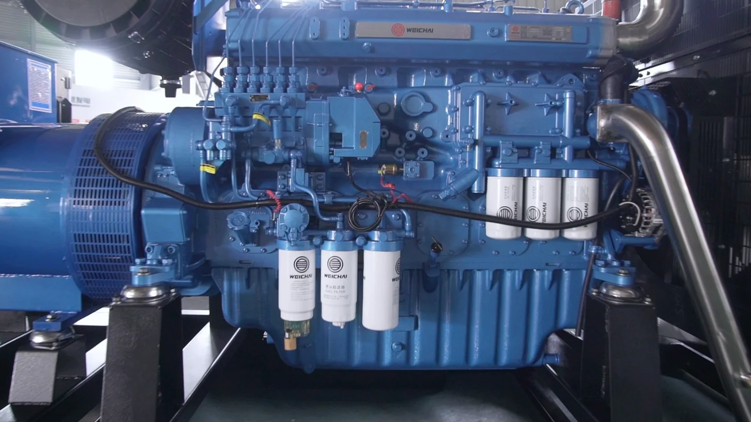 Blue engine showing filters, pipework and the alternator connection
