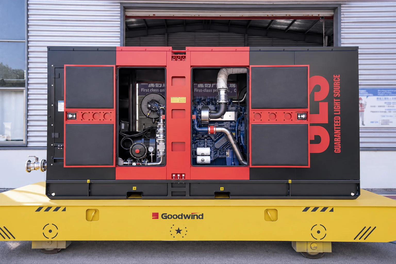 Red and black gas generator with canopy doors open, showing the engine and internal pipework at the GOODWIND factory