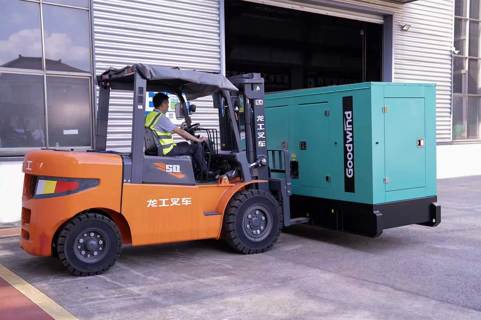 Forklift moving the enclosed GOODWIND diesel generator outside the factory workshop